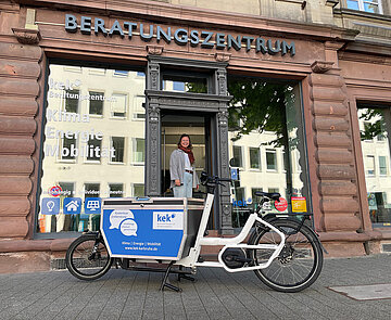 Foto von KEK-Büro mit Person in offener Tür und Lastenrad vor dem Laden