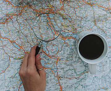 Hand hält Lupe über Stadtplan