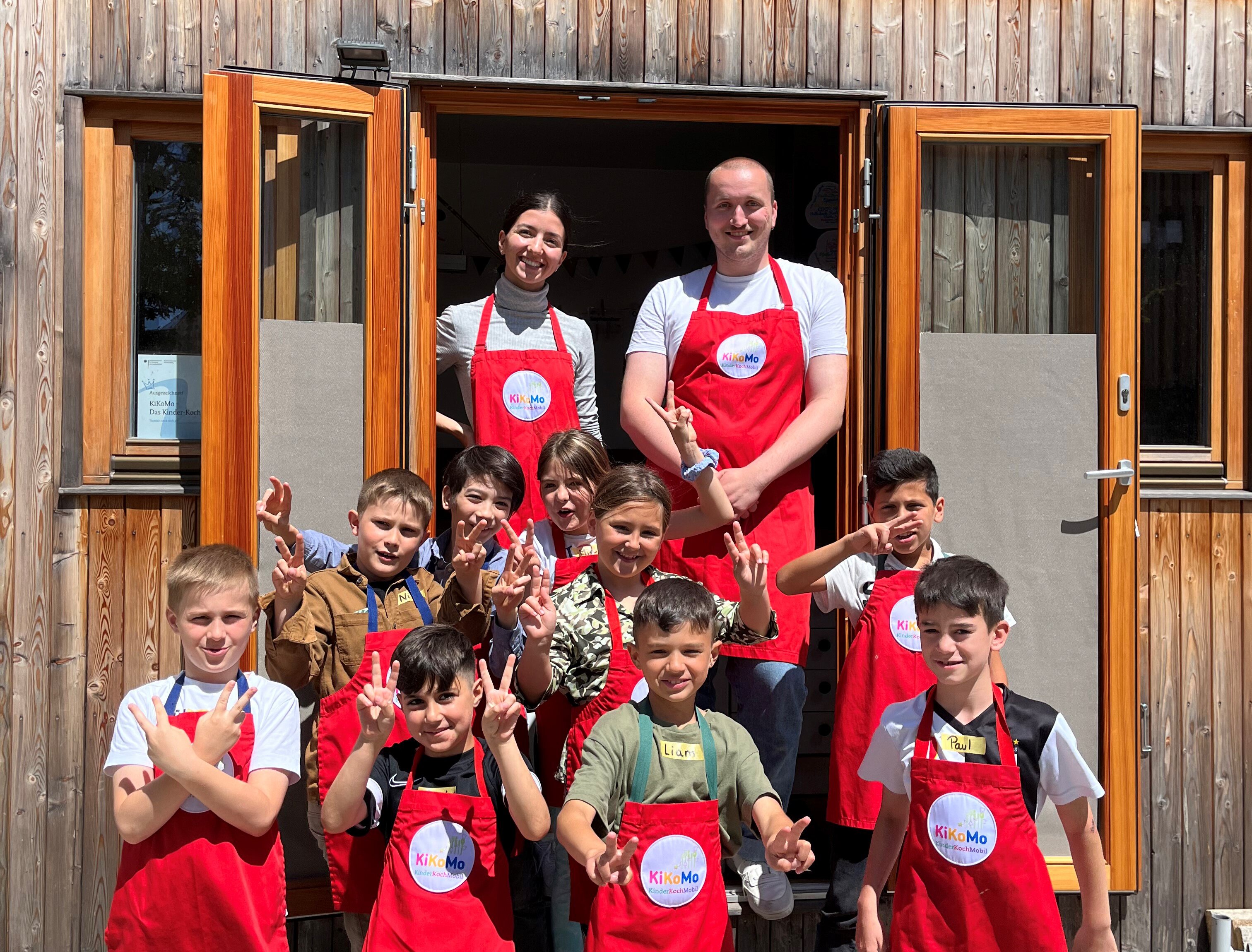 Kinder mit Schürzen posieren vor Tiny House 