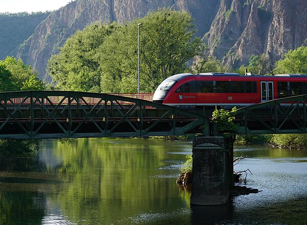 Regionalzug unterwegs in schöner Landschaft, über eine Brücke fahrend
