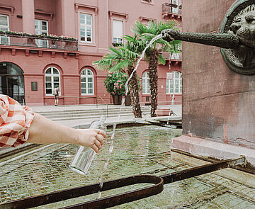 Brunnen Marktplatz - eine Flasche wird aufgefüllt
