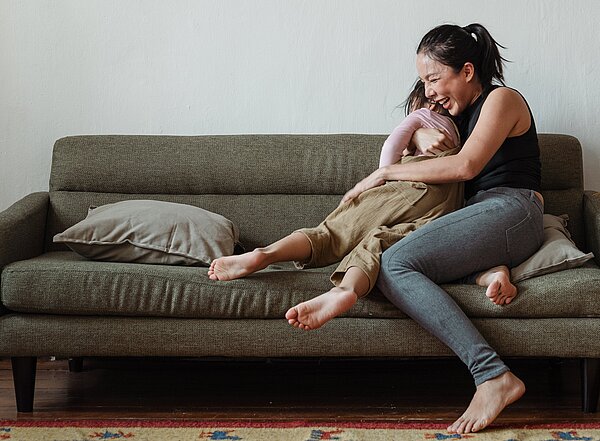 Mutter und Kind lachend auf Sofa