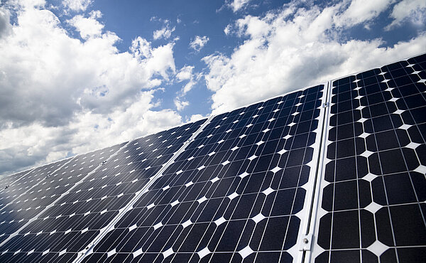 Das Symbolbild zeigt ein Solarpanel vor blauem Himmel mit Wolken.