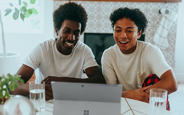 Zwei Personen schauen auf ein Tablet. Sie sehen fröhlich aus.