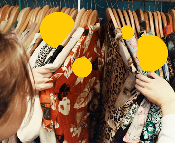 Person, die durch Kleider auf einer Kleiderstange schaut, gelbe Sphären zwischen den Kleidungstücken, Tatenbank-Bild für den Bereich Einkaufen