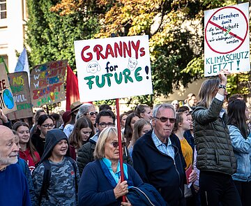 Klimademo mit vielen Menschen verschiedenen Alters und mit Schildern, die zu Klimaschutz aufrufen