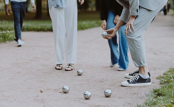Eine Gruppe Menschen spielt gemeinsam Boule.