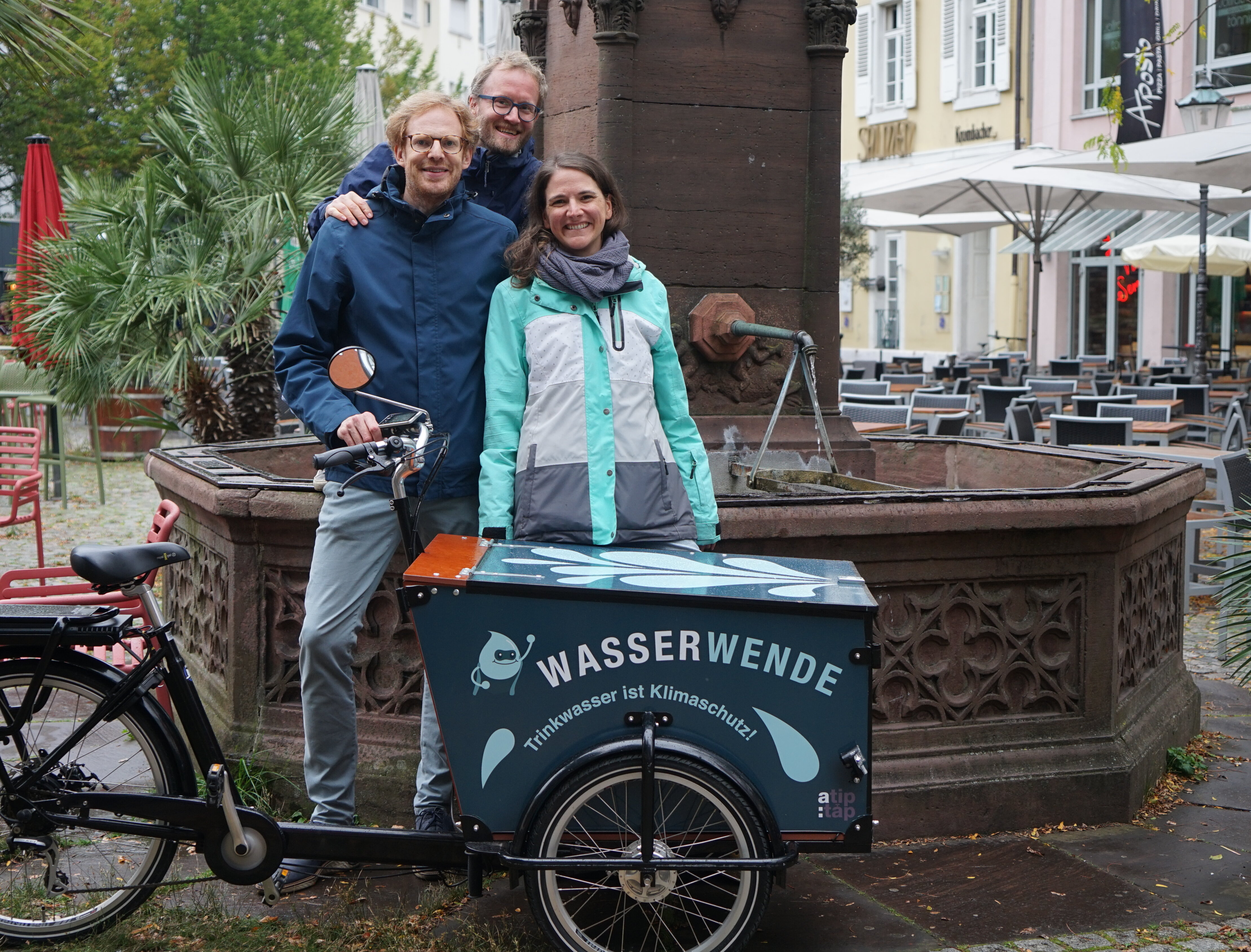 Drei Personen hinter Lastenrad mit Aufschrift Wasserwende