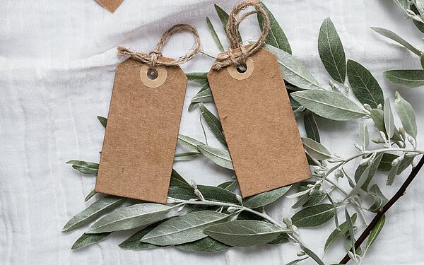 Geschenkanhänger und Tannenzweige auf einem weißen Tischtuch