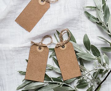 Geschenkanhänger und Tannenzweige auf einem weißen Tischtuch