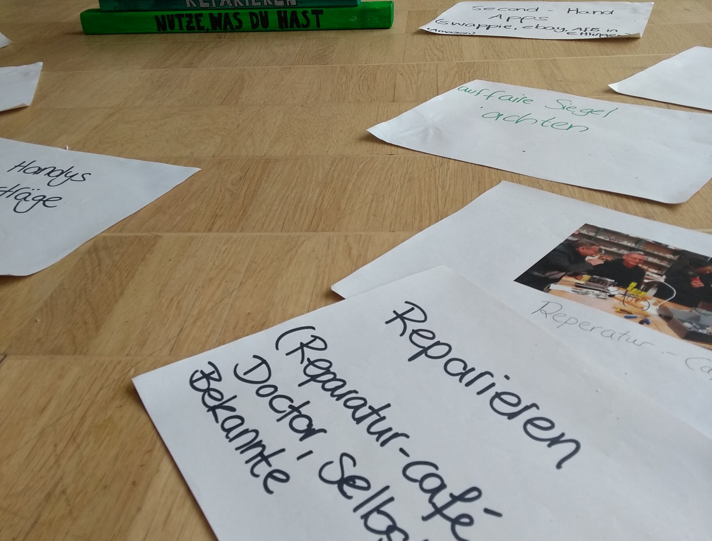 Szene in einem GloW Karlsruhe e.V.-Workshop, zu sehen ist der Boden eines Raumes mit einer bunten Konsumpyramide zu Elektronik 