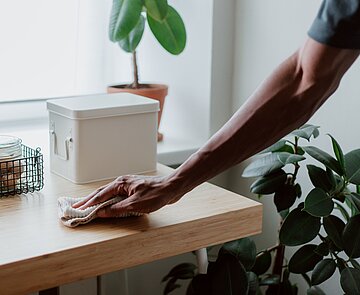 Hand, einer männlich gelesenen Person, putzt Tisch
