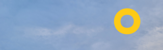 Ein Foto von blauem Himmel mit wenigen weißen Wolken, oben rechts ein gelber Kringel