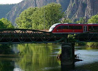 Regionalzug unterwegs in schöner Landschaft, über eine Brücke fahrend