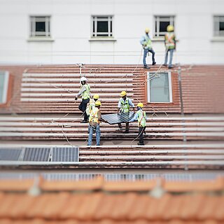Menschen auf einem Dach, beim Installieren von Solarpaneelen