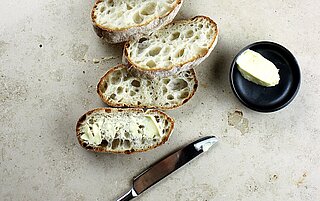 Ein aufgeschnittenes Brot, welches mit Butter oder Margarine bestrichen wird.