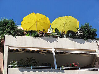 Zwei gelbe Sonnenschirme auf einem Balkon