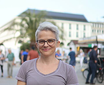 Porträt von Katrin Salzmann auf dem Karlsruher Marktplatz; lächelnde Frau mit Kurzhaarschnitt und Brille